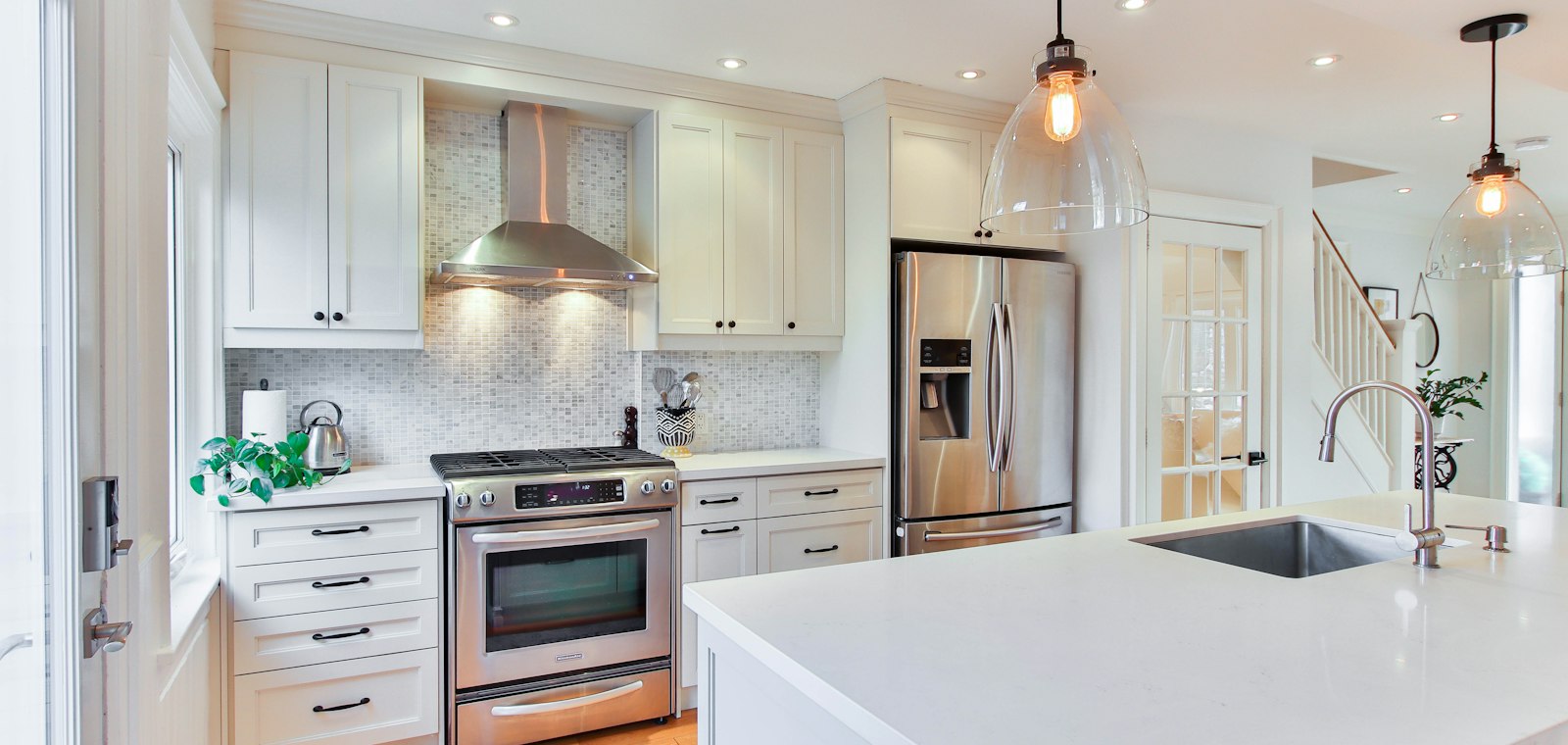 Modern kitchen with a stainless steel range hood, built-in refrigerator and quartz island, typical of premium Redwood City homes